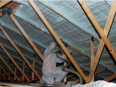 person applying spray foam to pole barn ceiling