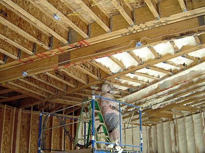contractor applying spray foam to garage ceiling