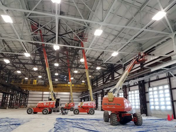 applying spray foam insulation on commercial building via multiple aerial lifts